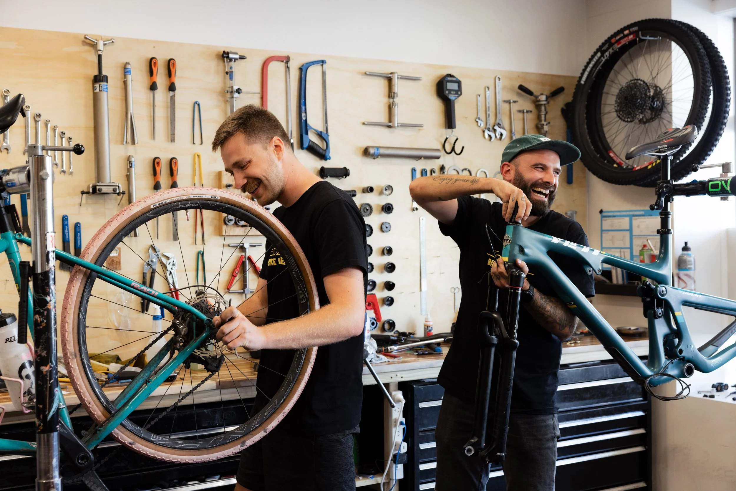 Mechanic inspecting bicycle wheels, tires, and spokes at a repair bench