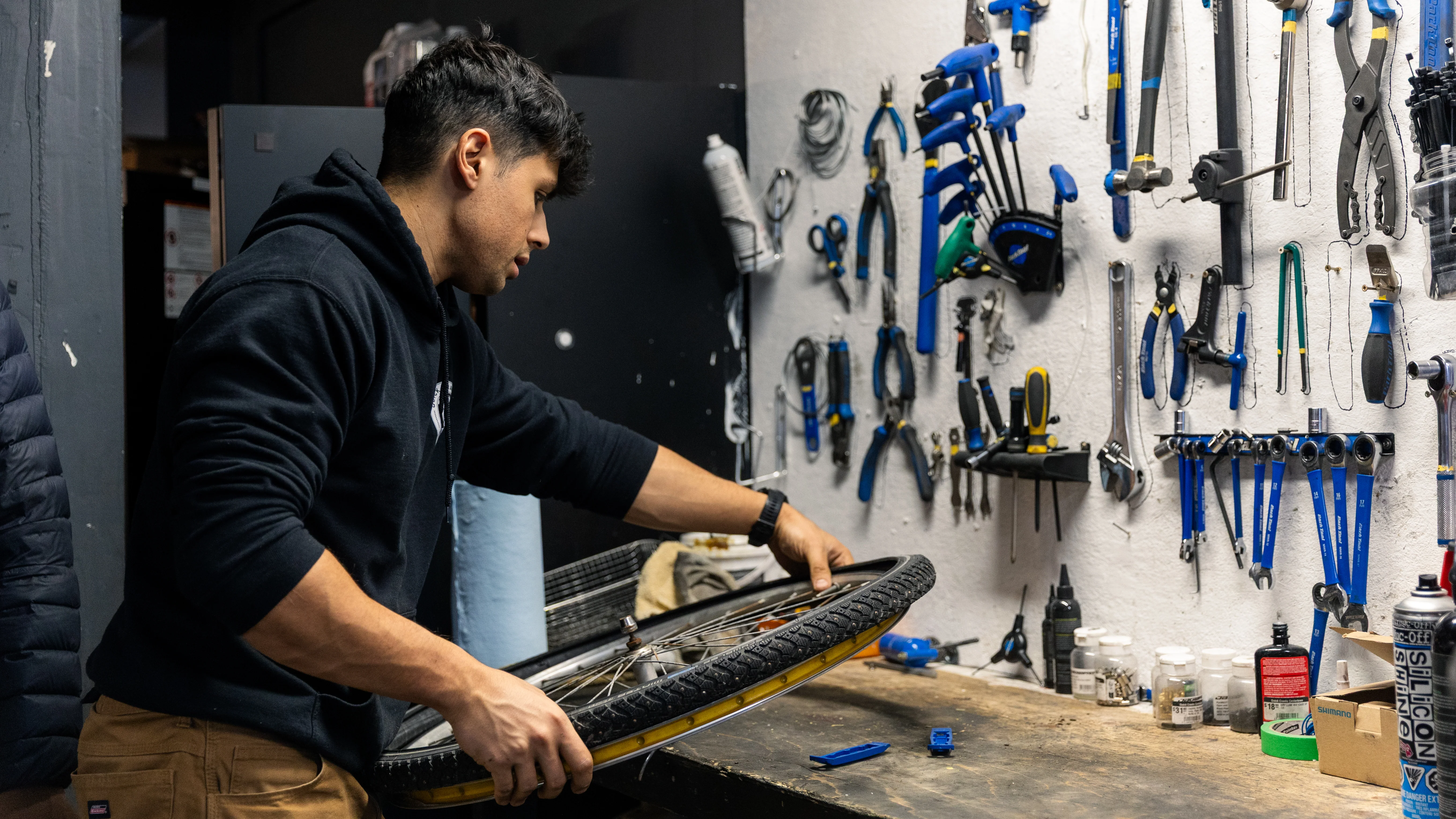 Bicycle service tools arranged beside a bike while a mechanic adjusts its components